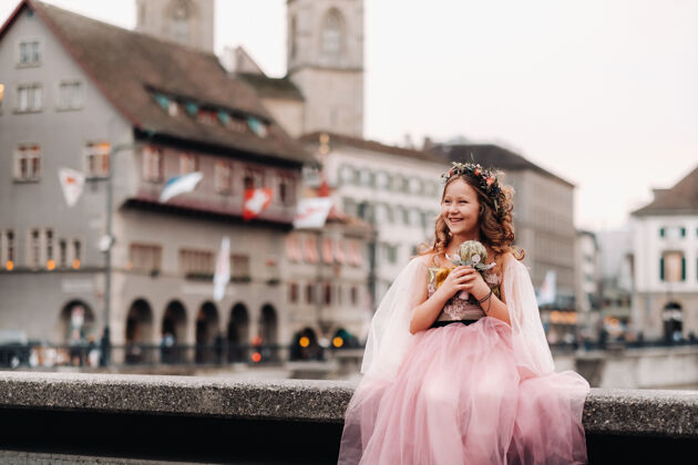 魅力一个穿着粉色公主裙的小女孩手里拿着一束花束 走在巴黎古城苏黎世肖像一个穿着粉色裙子的女孩在瑞士的城市街道上夏天孩子爱