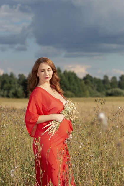 腹部美丽的孕妇在户外肖像期望公园