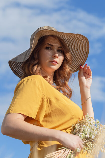 肥料在一个阳光明媚的夏日 一位年轻漂亮的孕妇穿着黄色的裙子 戴着黄色的帽子 走过一片麦田风景婴儿农村
