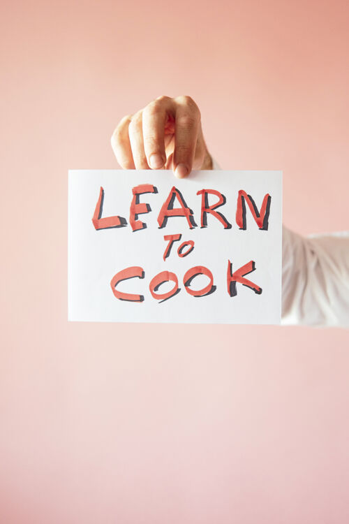 人一个人拿着一张粉红色背景上写着“学做饭”的纸的特写镜头角色帽子举行