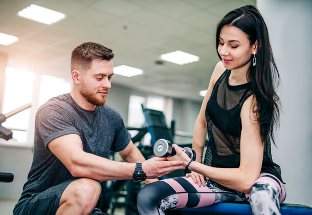 注意力集中健身教练在健身房锻炼客户男人运动肌肉