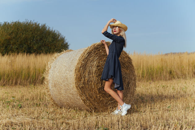 干草一位年轻漂亮的女村民在一捆干草旁摆出一身衣服田野姿势美丽