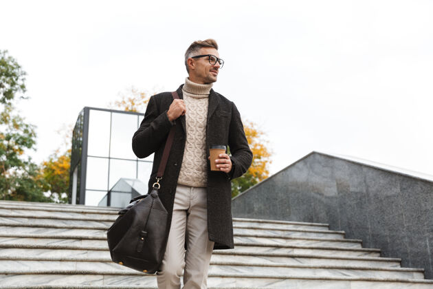 白种人30多岁的帅哥戴着眼镜 穿过城市街道 手里拿着外卖咖啡杯子街道成熟