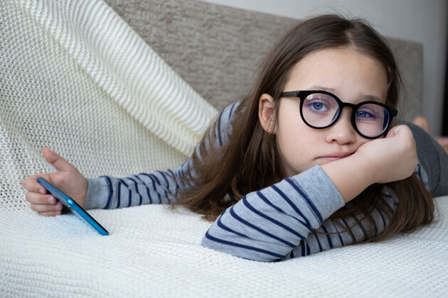 书戴眼镜的女孩在打电话 躺在沙发上舒适室内女孩
