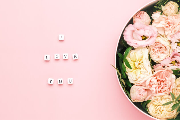 鲜花我爱你在木制方格上刻字 粉色背景上刻字 还有一个大的圆盒子礼物鲜花礼物