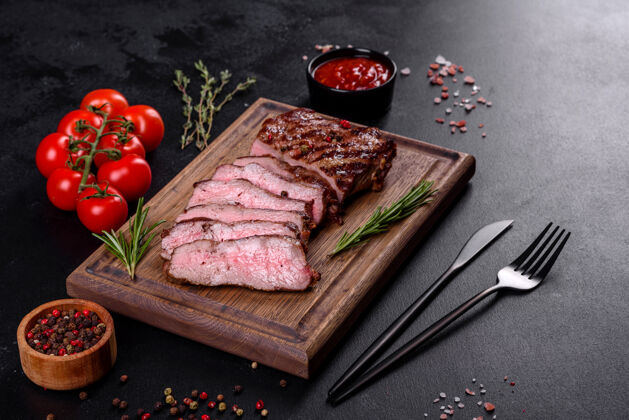 胡椒新鲜多汁美味的牛排 放在深色烤箱里表面.肉用香料和香草做的菜香草肉类叉子