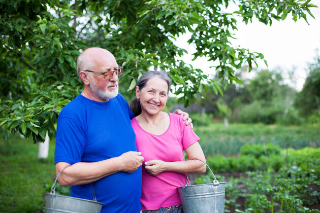 爱好菜园里两位老人拿着水桶两个夫妻年龄