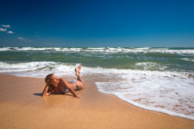 沙女孩躺在海浪中欣赏美丽的大海健康水自然