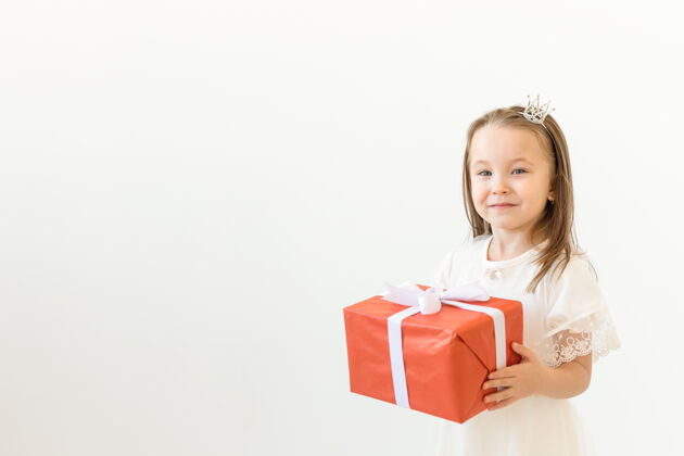 给予节日和礼物概念小女孩微笑着拿着白色的红色礼盒丝带盒子可爱
