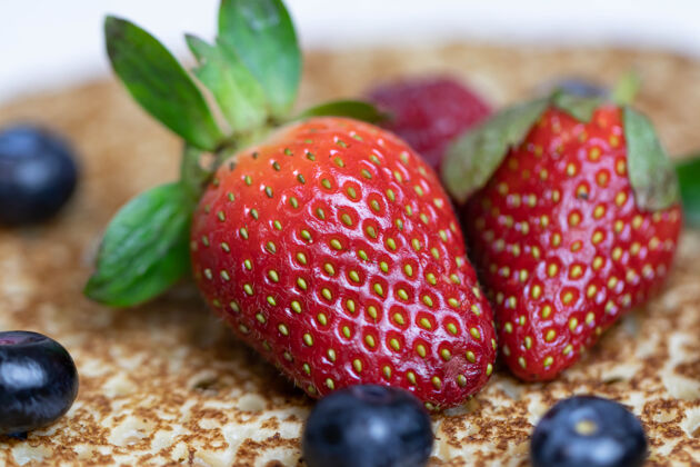 新鲜成熟多汁的草莓和蓝莓躺在美味的煎饼上俄罗斯料理国家菜 带新鲜浆果饮食五颜六色装饰性