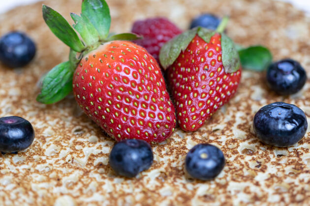 传统成熟多汁的草莓和蓝莓躺在美味的煎饼上俄罗斯料理国家菜 带新鲜浆果煎饼水果甜点