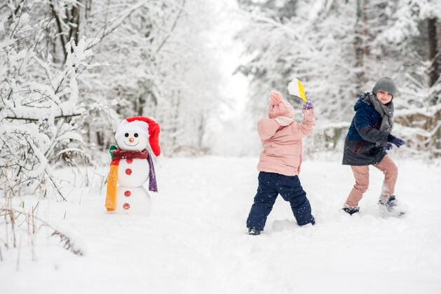 女孩可爱的男孩和女孩在冬天的白森林堆雪人冬天霜冻男孩