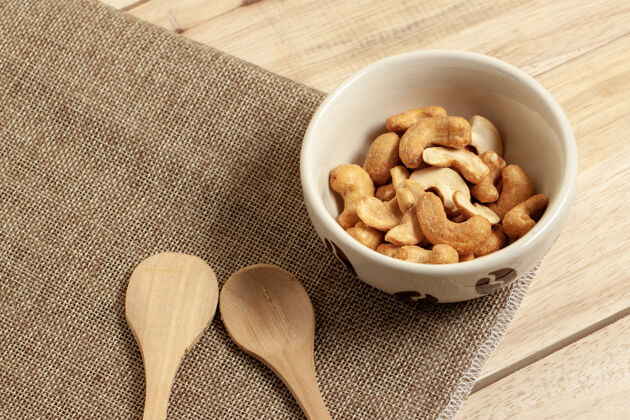 坚果收起腰果花生干粮小吃放在碗里放在麻袋和木桌上餐桌盐健康