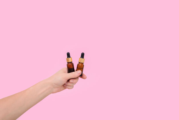 胶原蛋白化妆品血清在透明玻璃滴管瓶在粉红色的背景在一个女人的手天然护肤品的概念精华护肤品 美丽健康肌肤血清滴管瓶药品