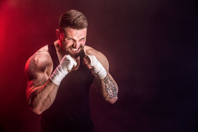 男子泰拳运动员在黑墙上与烟搏斗运动概念打攻击性肌肉
