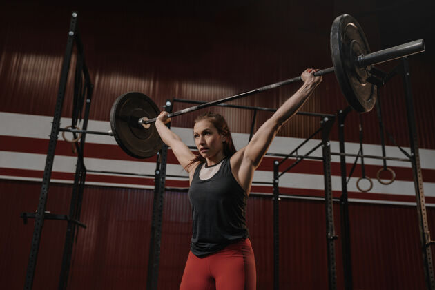 体操戒指年轻肌肉发达的女子在家做举重练习健身房健身女运动员在体育馆举重举重运动力量