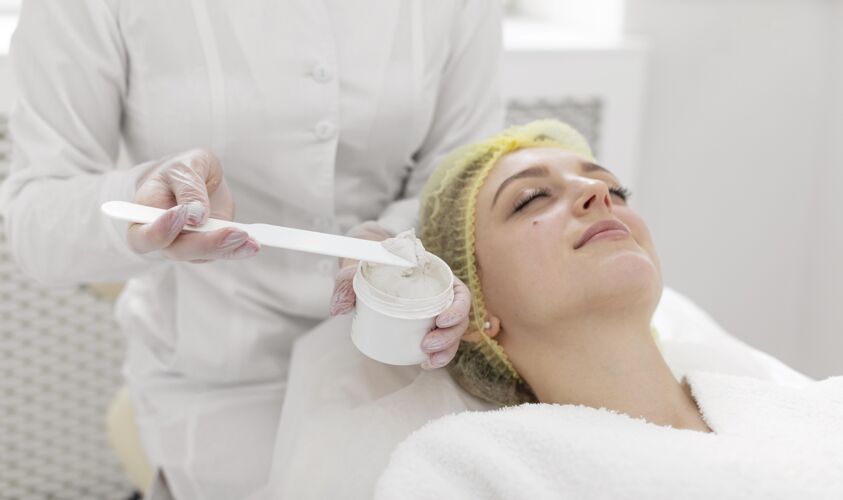 化妆品在美容诊所做面部护理的女人美容常规客户面部护理