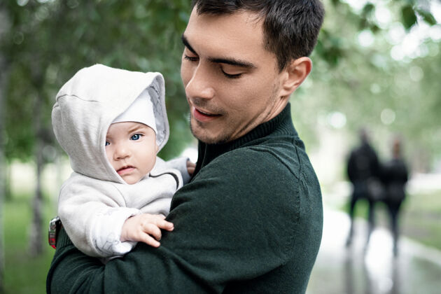 认证爸爸穿着绿色夹克 抱着孩子在公园散步自拍新生儿关爱