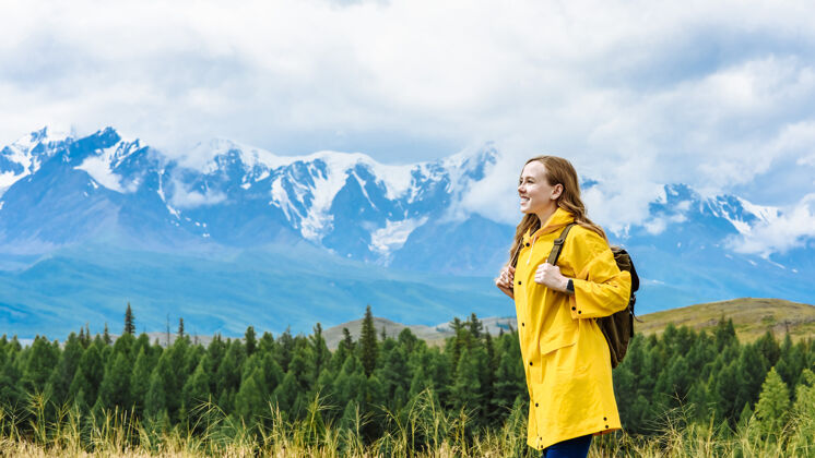 山谷女游客背着背包远眺雪山中的山峰度假女人年轻人山