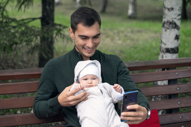 单身父亲快乐的父亲和坐在长椅上的新生婴儿自拍做父亲概念父母爱自拍