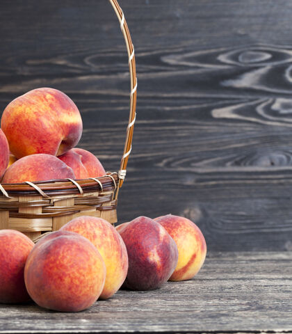 水果成熟可口的桃子放在篮子里 站在黑色的木桌上甜食立场健康