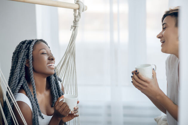 非裔美国人感觉放松二女孩们在光线充足的房间里喝咖啡 看起来很放松仅限女性放松两个人