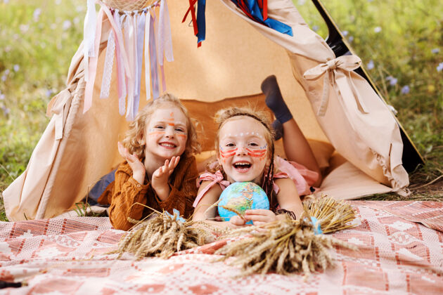 民间两个快乐的小女孩脸上都是美洲土著人的妆 在维格瓦姆的房子里 夏天在户外玩得很开心孩子和平波西米亚