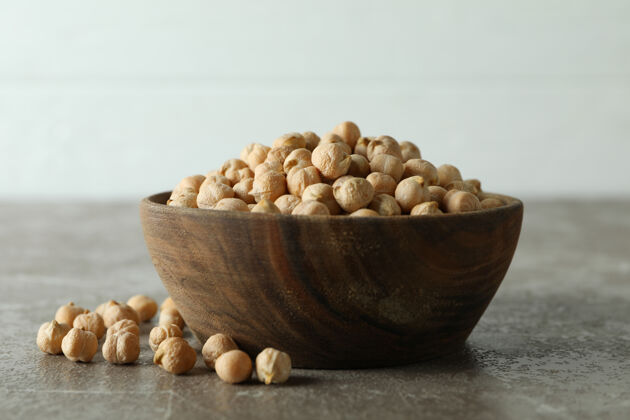 蛋白质灰色桌子上放着新鲜鹰嘴豆的木碗生的堆木材