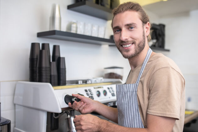 满意最喜欢的工作忙快乐的年轻胡须男子倒咖啡水 而在他的咖啡馆千禧一代转身小企业