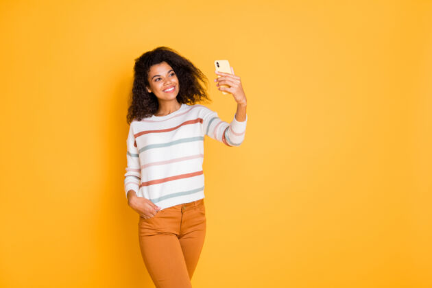 拍摄可爱的卷发女孩的肖像使用数码手机自拍非洲微笑博客