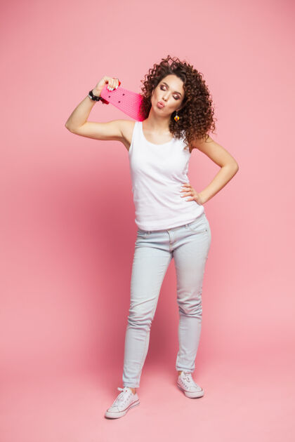 女性全高的搞笑时髦女孩与粉红色长板超过粉红色长板运动鞋短裤