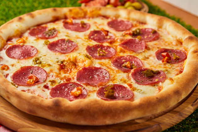水平传统的意大利披萨 意大利香肠 意大利香肠 意大利马苏里拉和罗勒放在绿草上聚会辛辣洋葱