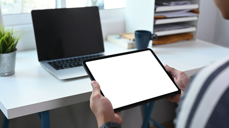 电子特写镜头的年轻人自由职业者与笔记本电脑和使用数字平板电脑在家办公消息网络手持