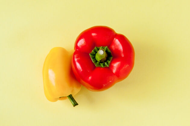 辣椒整个黄色和红色的甜椒或辣椒在黄色背景上。五颜六色有机配料