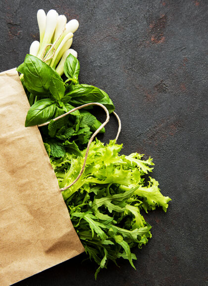 蔬菜在一张黑桌子上的纸袋里放着新鲜的绿色蔬菜配料营养吃