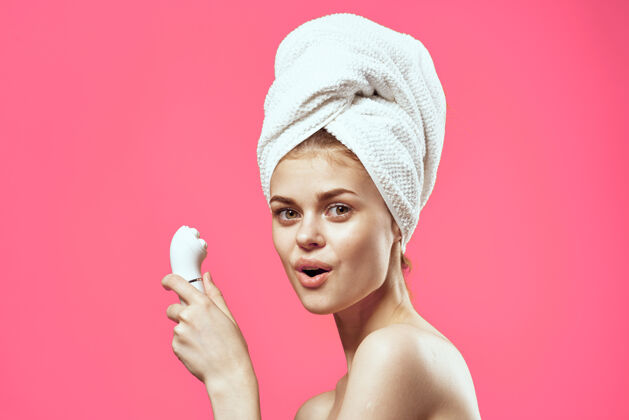 激光女人用毛巾在头上裸肩美容面部按摩器美容师清洁年龄
