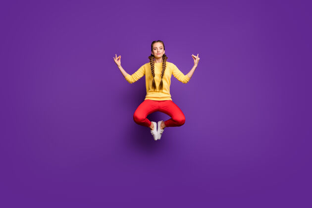 长全身疯狂的年轻女士跳莲花高姿势放松瑜伽训练穿休闲黄色套头衫红色长裤隔离紫色墙壁暂停年轻灵感