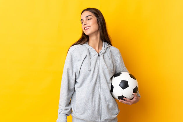 成年人年轻的足球运动员女人在黄色背景下笑孤立积极女人深色头发