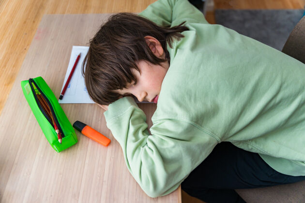 教学十岁的小男孩坐在桌子旁做作业回家累了孩子睡觉的时候在课桌上做运动房子小学知识