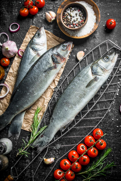 美味生鱼鲈鱼在网格上与番茄和香料在黑暗的乡村桌子上海鲜捕获自然