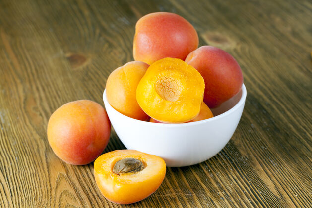 特写盘子里放着新鲜的杏子 有些杏子被切成两半 水果的颜色很漂亮混合餐多汁