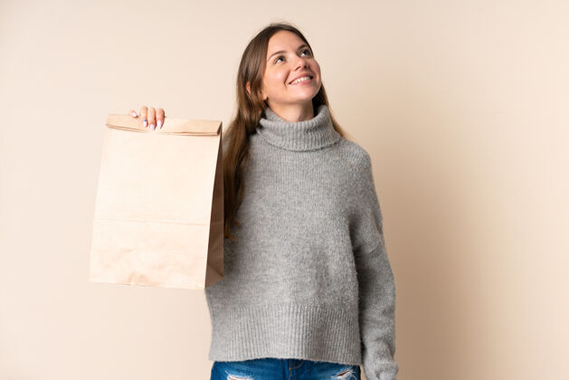 幸运年轻的立陶宛妇女拿着一个购物袋 微笑着抬头看营养思考食物