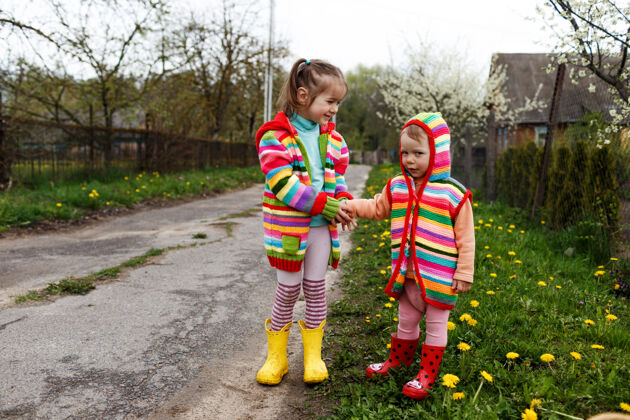 天空两个穿着鲜艳衣服的小女孩在黄色的树林里互相握着手蒲公英快乐童年孩子抱微笑