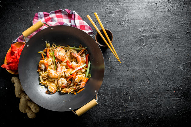 辣椒粉把乌冬面放在炒锅里 用酱油 筷子和餐巾纸放在黑木桌上菜肴午餐虾