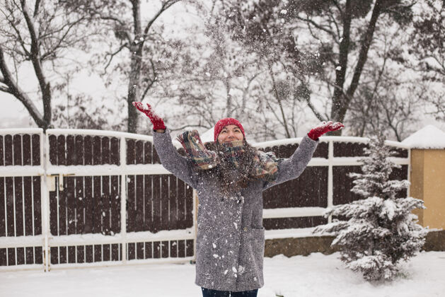 美丽一个女孩站在冬天的背景下扔雪户外天空人