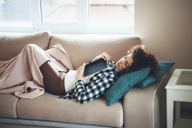 放松一个卷发的学生在读完一本书后 正躺在被单上睡觉学习室内累