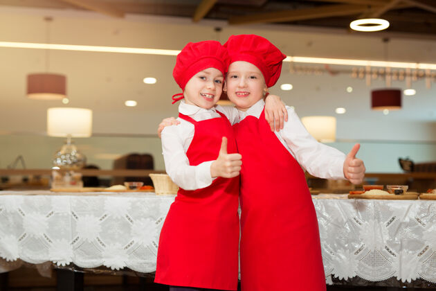 围裙两个穿着白衬衫和红围裙的漂亮厨师女孩在餐厅做比萨饼正面肖像餐馆