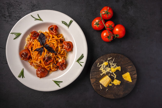饮食意大利面配烤樱桃番茄 磨碎的帕尔马干酪和香蒜酱 背景为深石墨色 俯视图 复制空间传统配料景观