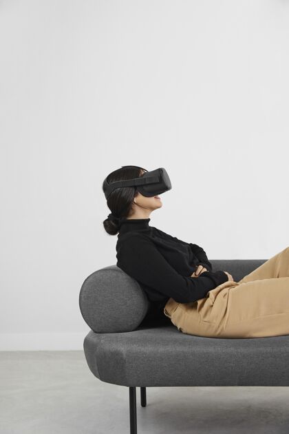 女人沙发上戴着虚拟现实耳机的女人设备虚拟现实耳机室内