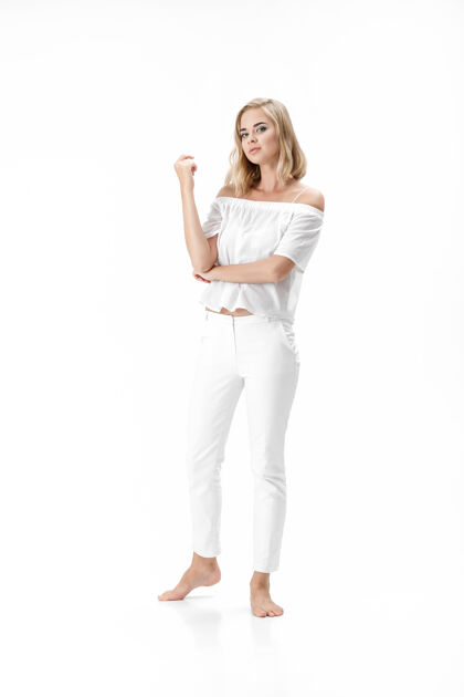 模特美丽严肃的金发女人在白色的背景上穿着白色的衬衫和裤子年轻背景性感